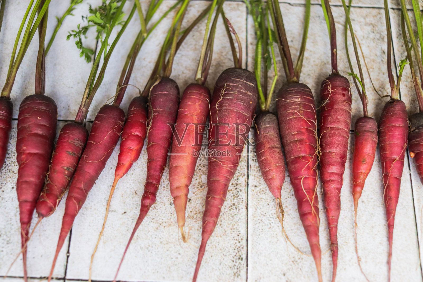 有机胡萝卜收获与明亮的橙色色调核和紫色皮在灰色的桌子上的特写照片摄影图片