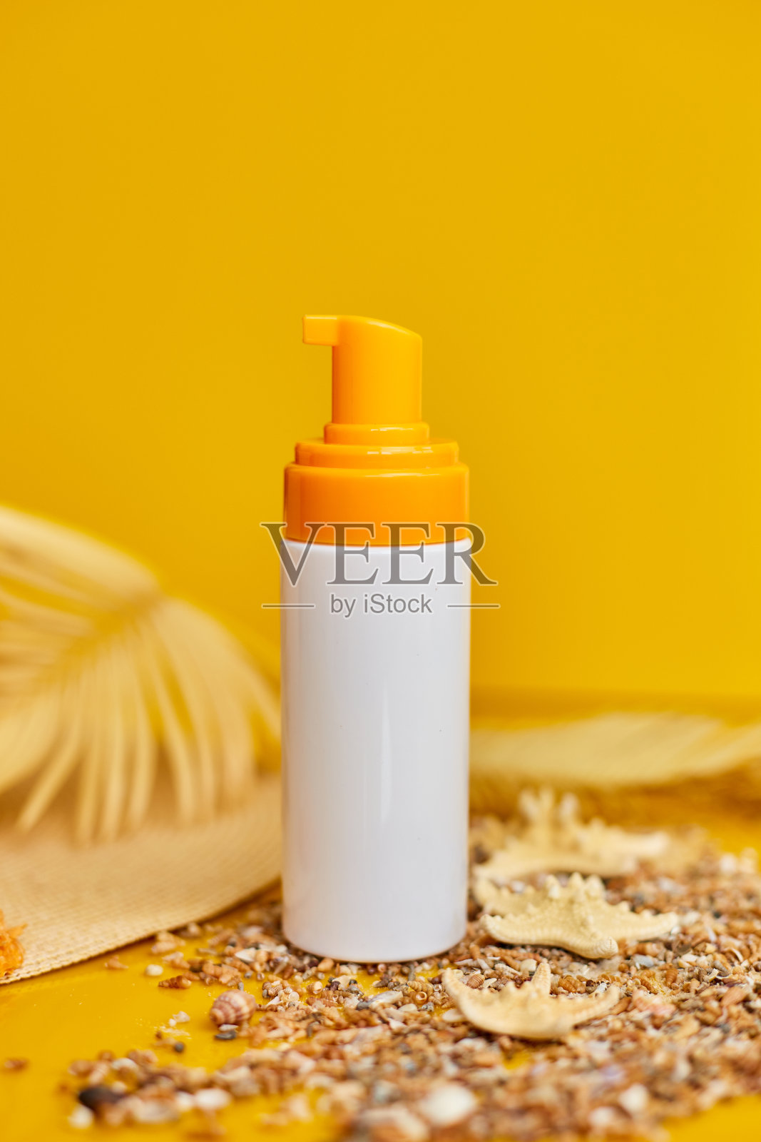 防晒管模型以贝壳、沙黄色为背景，暑假防晒防紫外线护肤概念。照片摄影图片