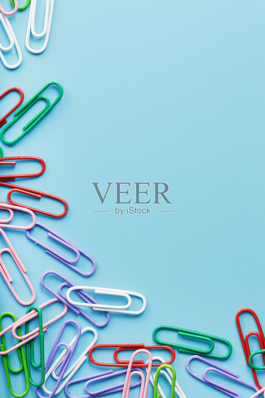 蓝色背景上的彩色回形针。照片摄影图片