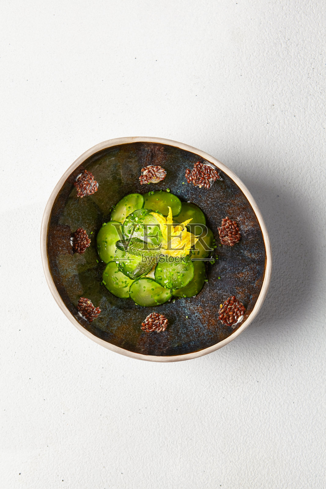 手工陶瓷碗泡黄瓜。新鲜的黄瓜片和松茸在创新的食谱照片摄影图片