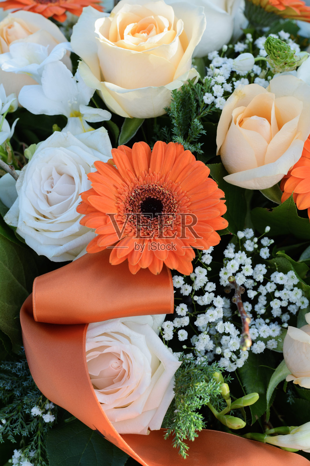 花束中有一朵橙色非洲菊。几朵美丽的橙色和白色的花在阳光下。橙色非洲菊和一束其他的花照片摄影图片