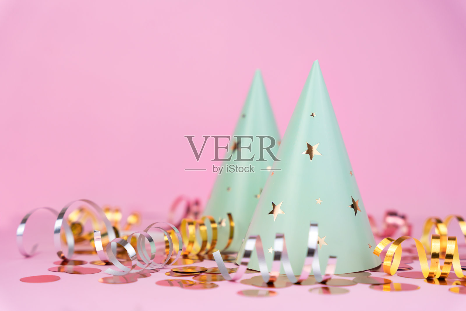 粉红色背景上有星星和节日装饰的聚会帽。副本的空间。特写镜头。照片摄影图片