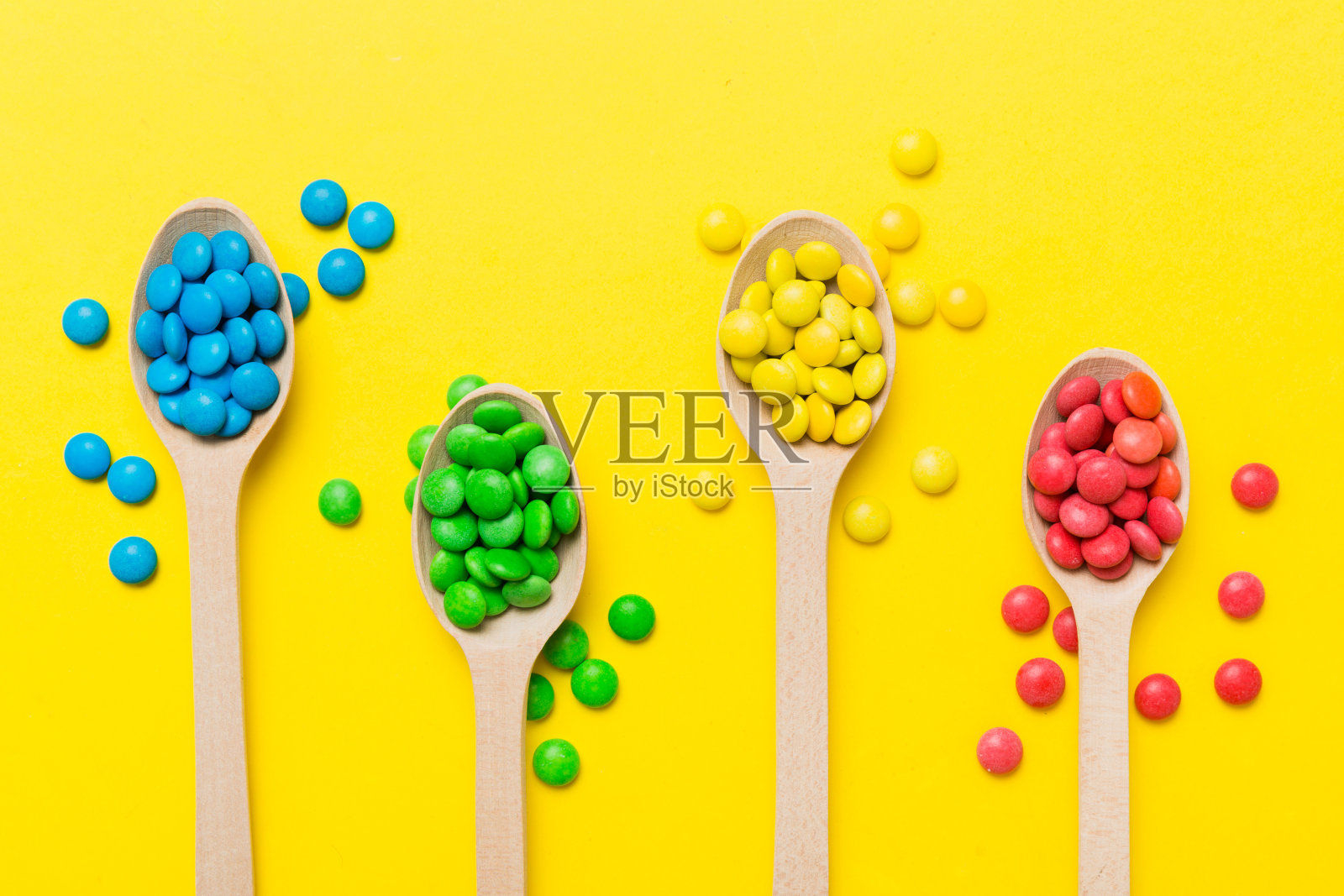 美味的彩色糖果勺子在彩色背景。糖果装饰顶视图与复制空间照片摄影图片