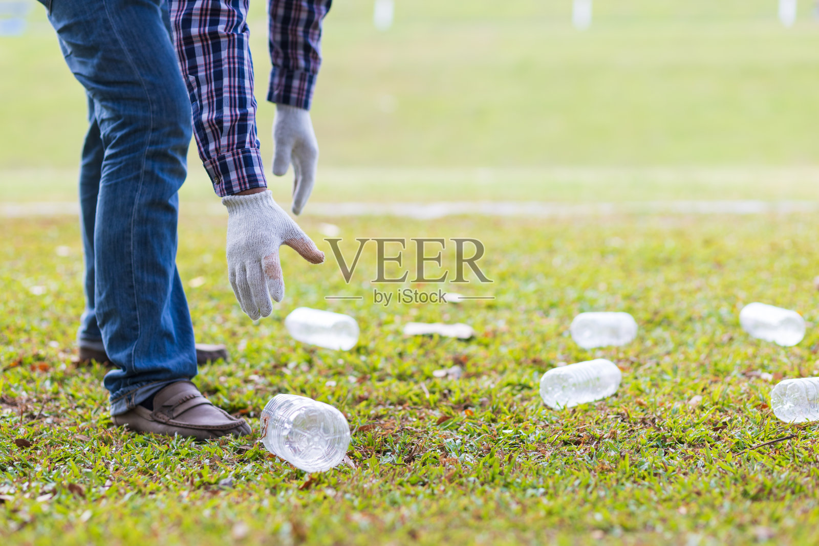 志愿者们在公园的草坪上捡塑料瓶。照片摄影图片
