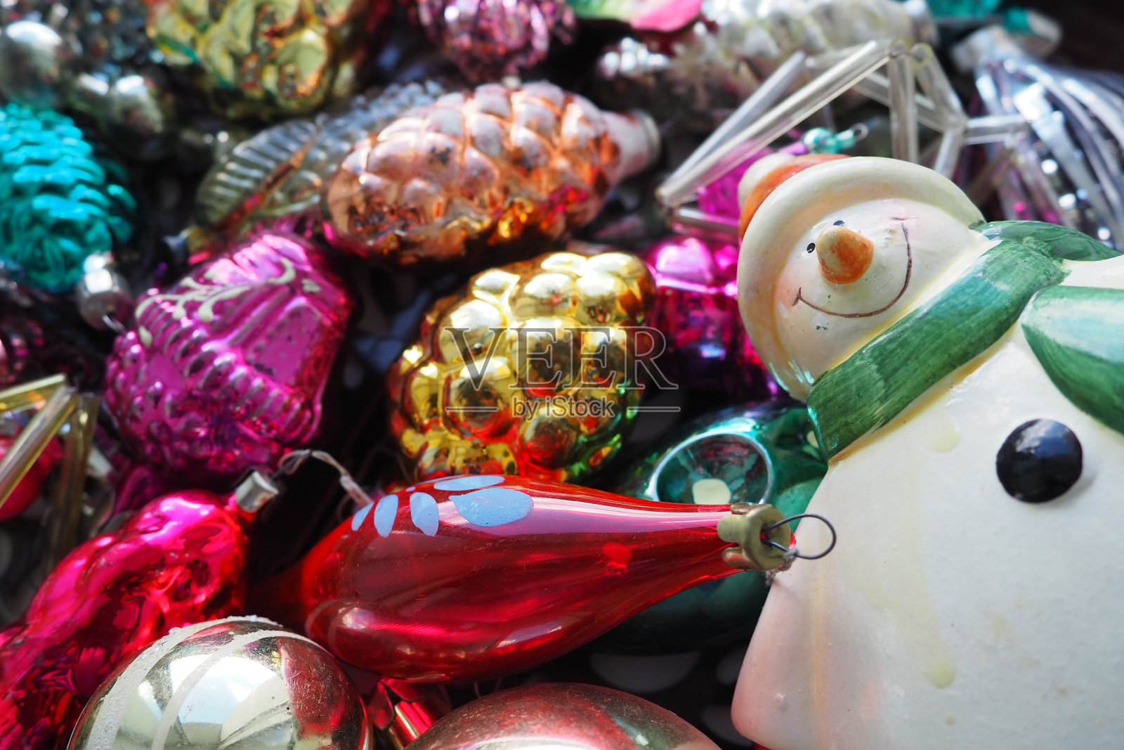 欢快微笑的陶瓷雪人在绿色围巾和冬天的帽子。新年和圣诞节的装饰，金箔。多种颜色的圆锥形球。节日的室内装饰。新年或圣诞节照片摄影图片