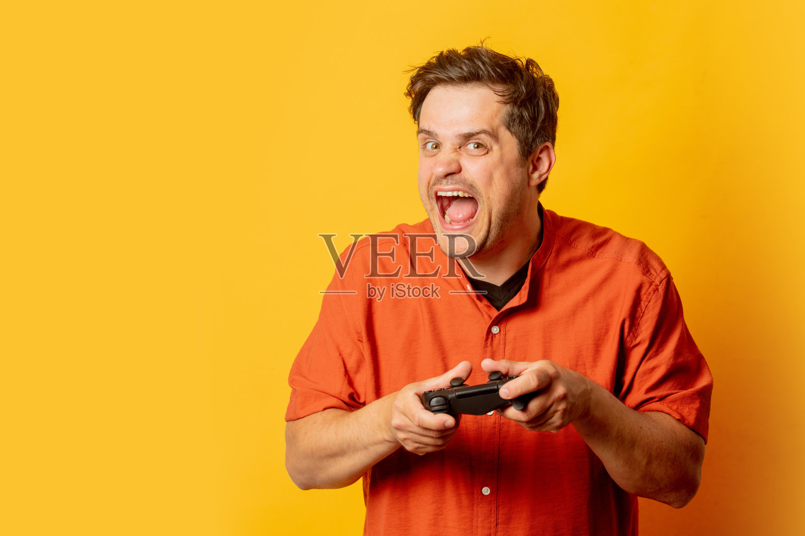 兴奋的家伙在黄色背景上玩游戏控制器照片摄影图片