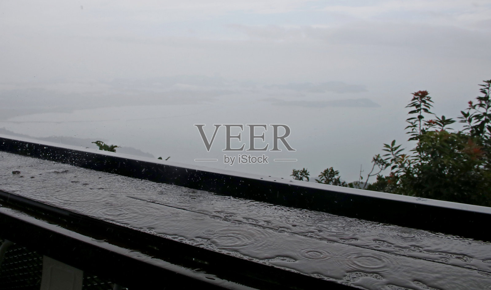 远处有雾，下着大雨，窗台上有水。照片摄影图片