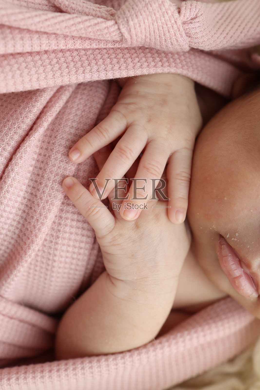 新生婴儿的小手。穿着粉色衣服的新生儿柔软的手。新生儿的手指靠近。工作室微距摄影。女人的幸福。的概念。照片摄影图片