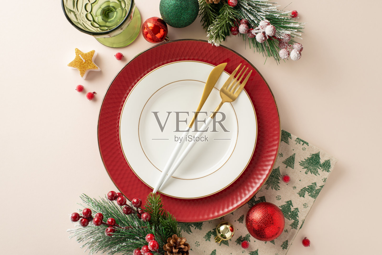 优雅的节日餐桌为新年除夕在高档餐厅聚会。俯视图盘子，餐具，餐巾纸，酒杯，装饰，冬季常绿树枝，浆果在柔和的米色背景照片摄影图片