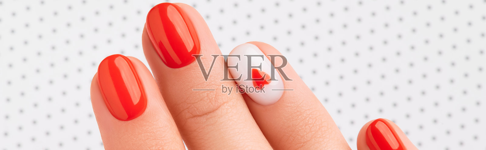 女人的手与时尚的红色指甲在白色的背景。情人节美甲设计照片摄影图片