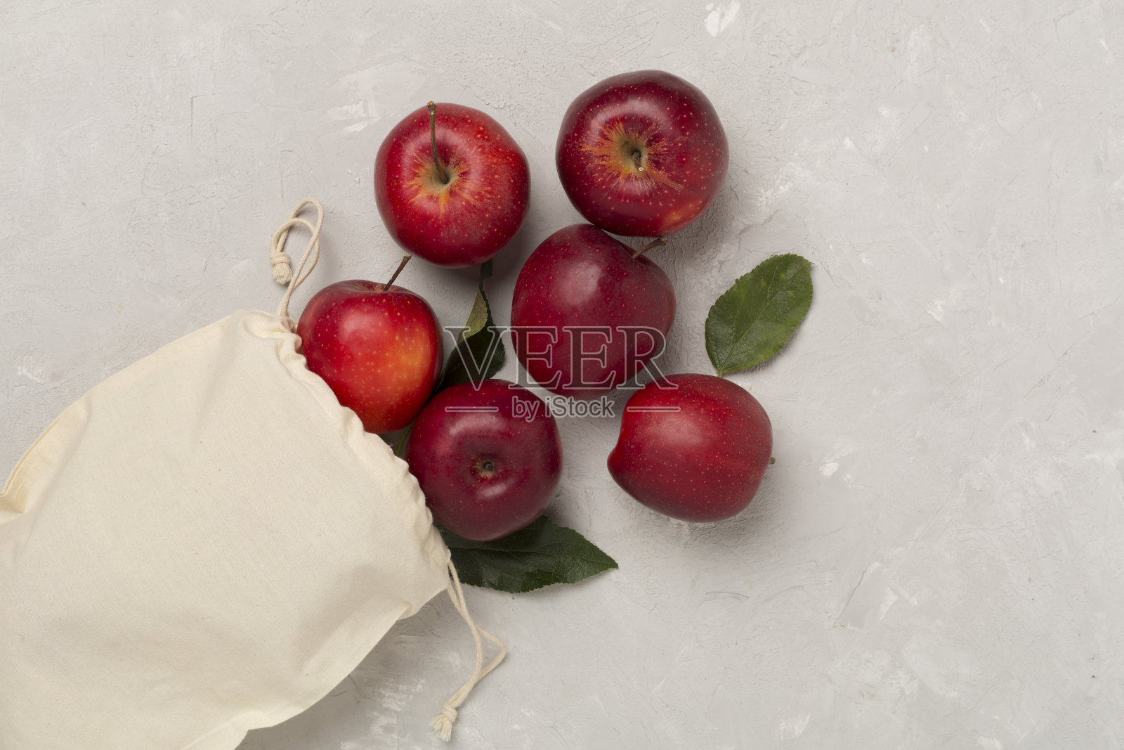 混凝土背景上的新鲜红苹果和树叶，俯视图照片摄影图片