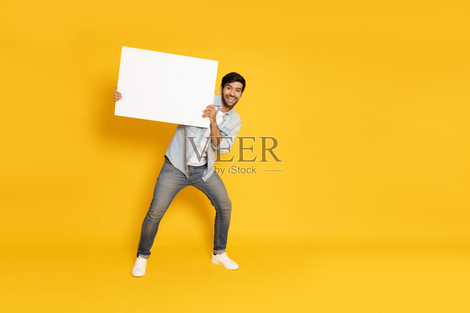 年轻人展示并拿着黄色背景的空白白色广告牌照片摄影图片