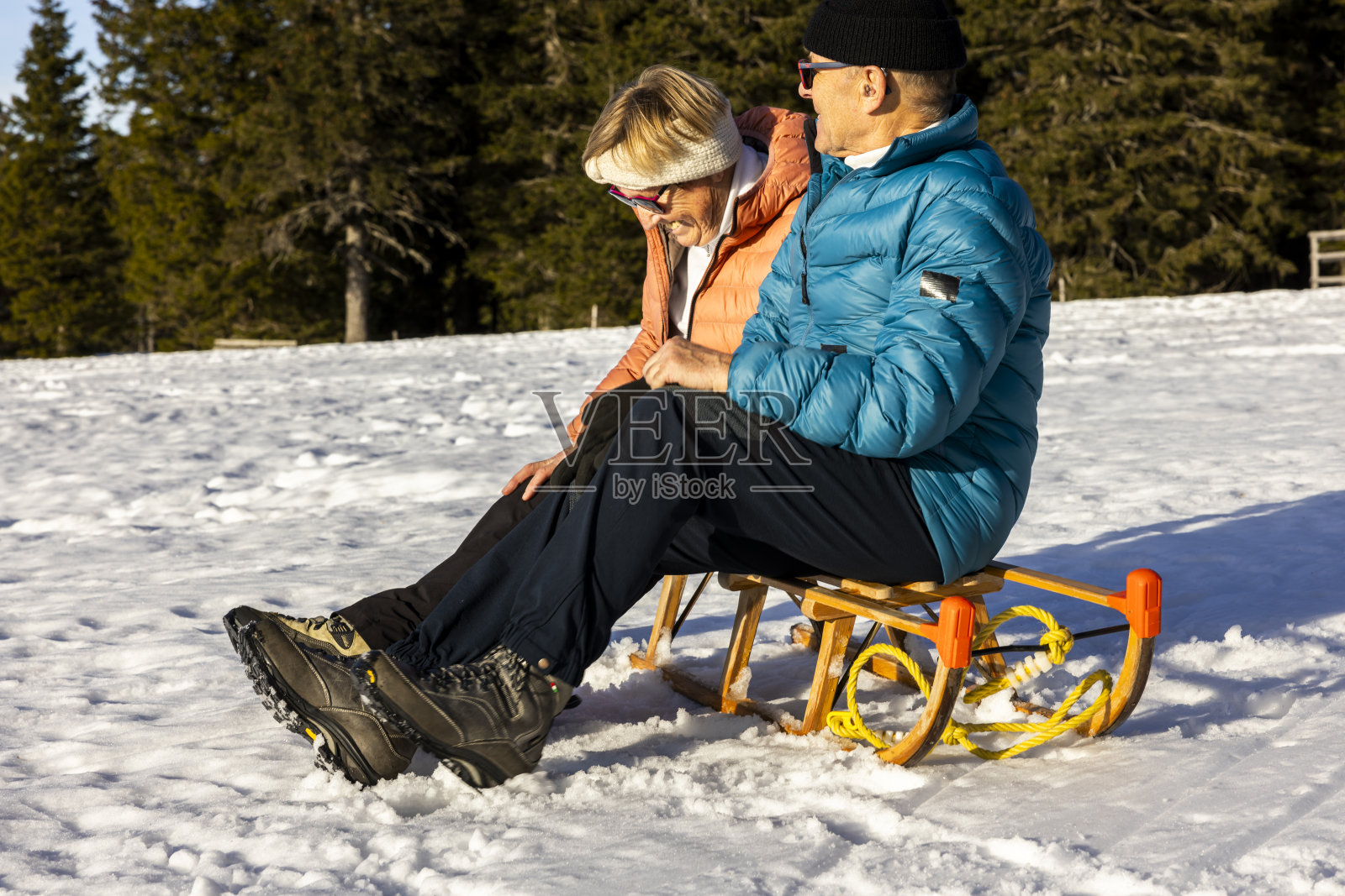 幸福的老夫妇坐在雪坡上的雪橇上照片摄影图片