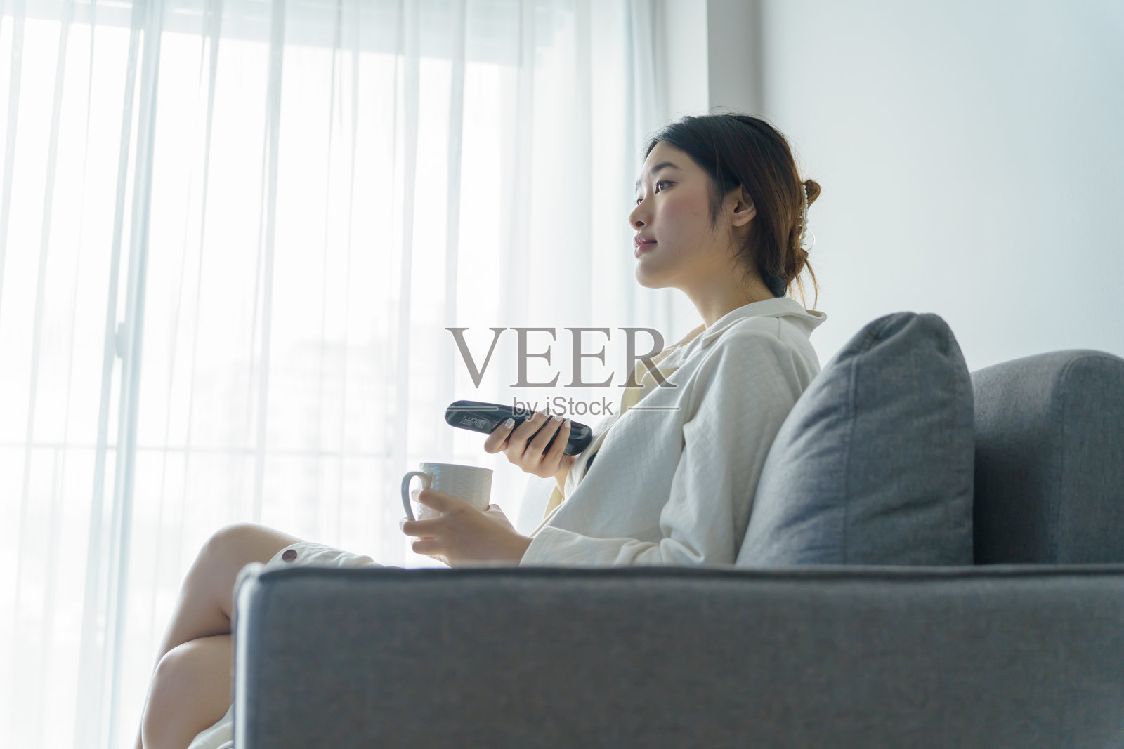 看智能电视和使用遥控器的女人。照片摄影图片