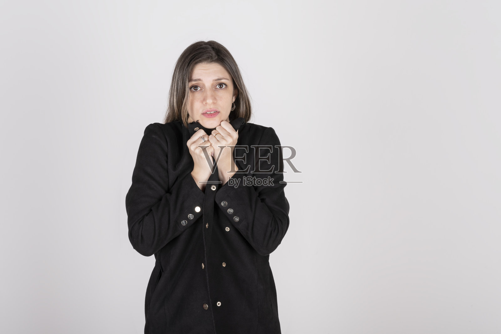 画室里一个年轻的金发女人的肖像，她穿着黑色的外套，脸上带着冷漠和厌恶的表情照片摄影图片