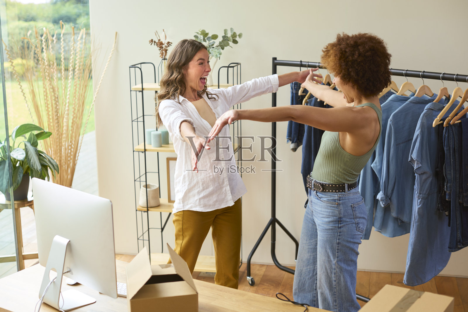 两位女性朋友在家一起庆祝她们在线时尚事业的成功照片摄影图片