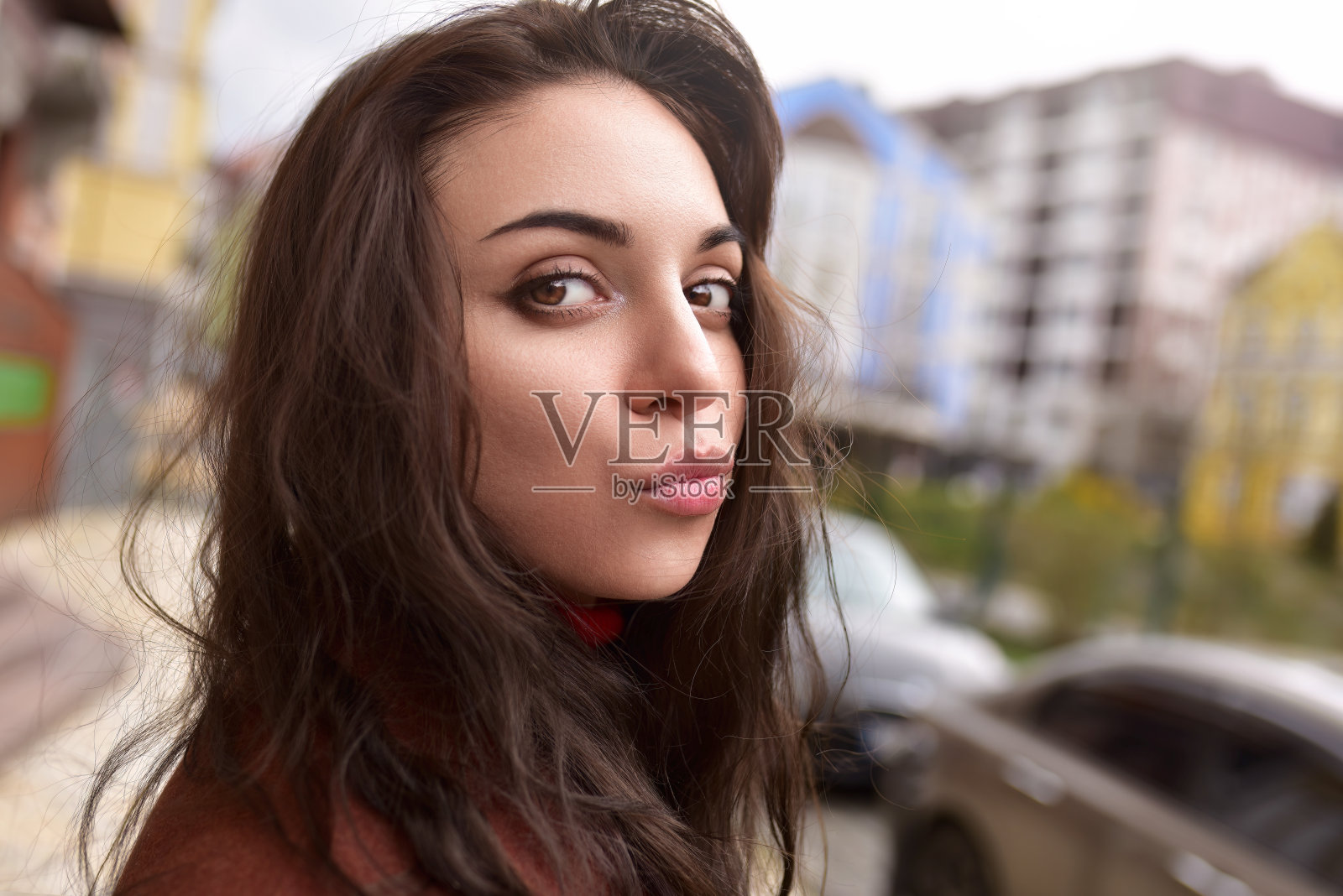 一个穿着秋天棕色大衣的漂亮时髦的女人在街上给我一个吻。照片摄影图片