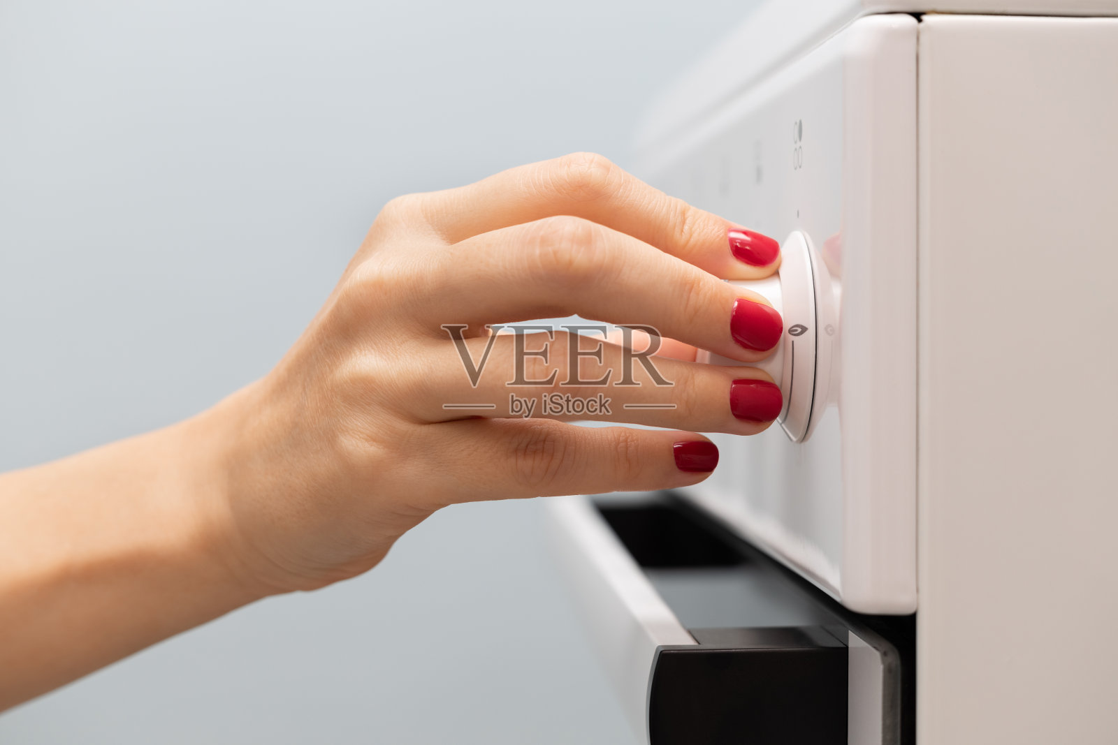 一位妇女的手转动煤气炉上的选择器照片摄影图片