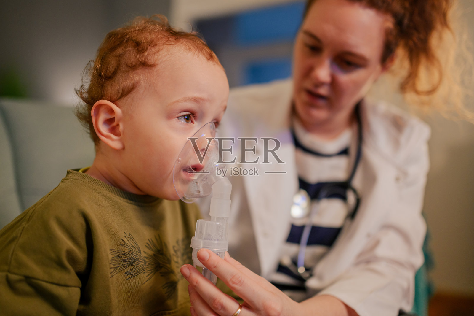 一个生病的小男孩正在通过雾化器和吸入剂接受药物治疗。照片摄影图片