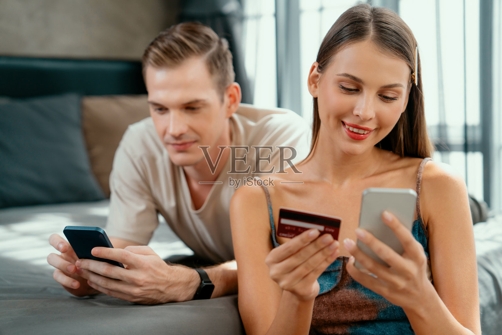 年轻夫妇坐在卧室里使用在线支付应用照片摄影图片