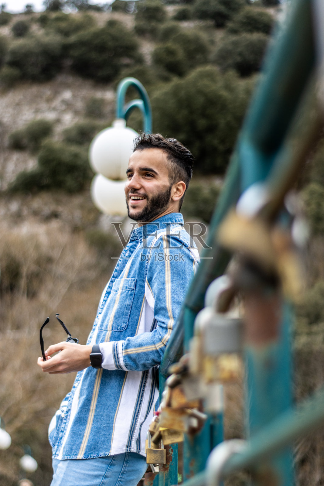 一个时髦的年轻人背靠在扶手上，手里拿着墨镜照片摄影图片