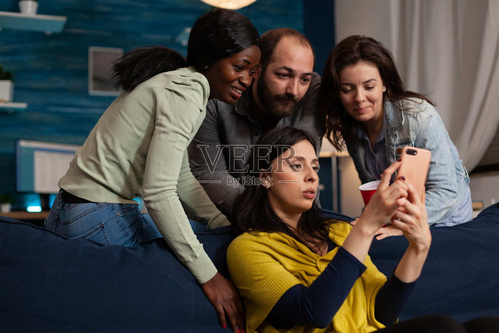 电影之夜，多民族朋友在家里用智能手机看搞笑视频照片摄影图片