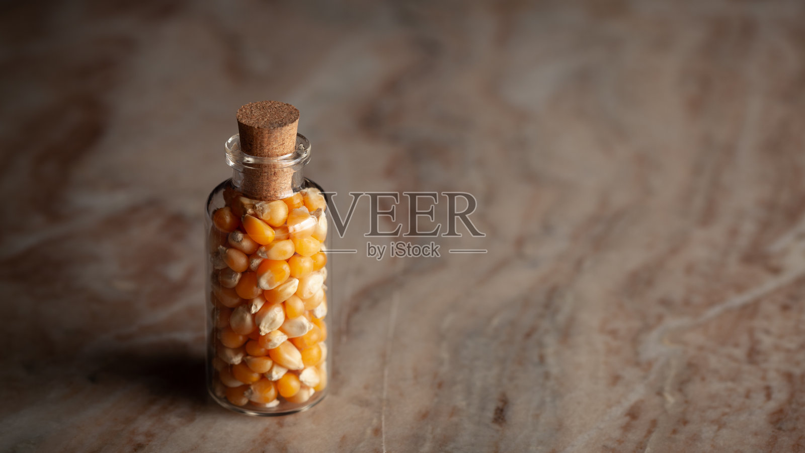 一个装满有机玉米种子的小玻璃瓶。照片摄影图片