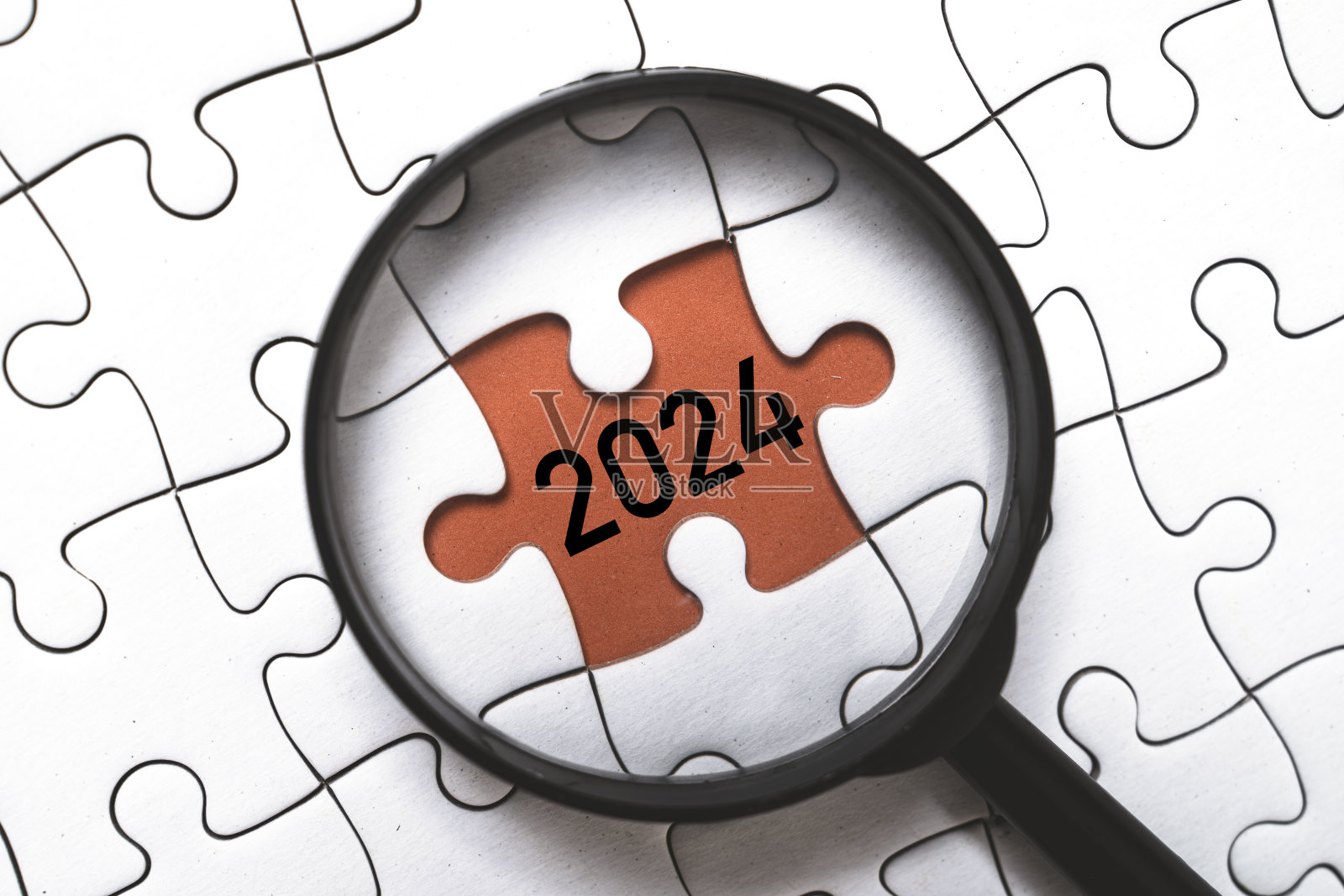 聚焦于2024年新年概念的放大镜玻璃和拼图里面。照片摄影图片