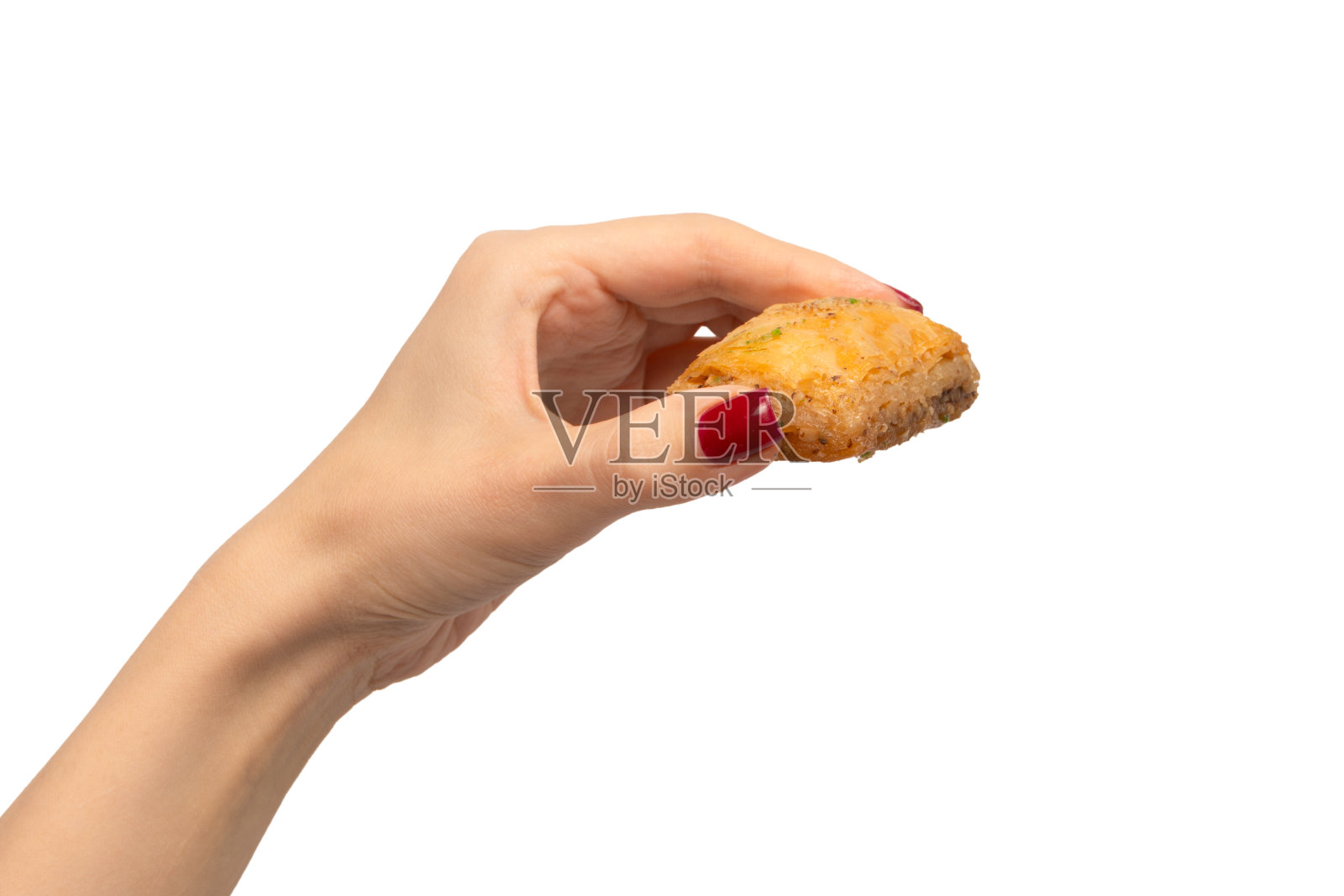 美味甜美的果仁蜜饼在女人的手与红指甲孤立在白色的背景。照片摄影图片