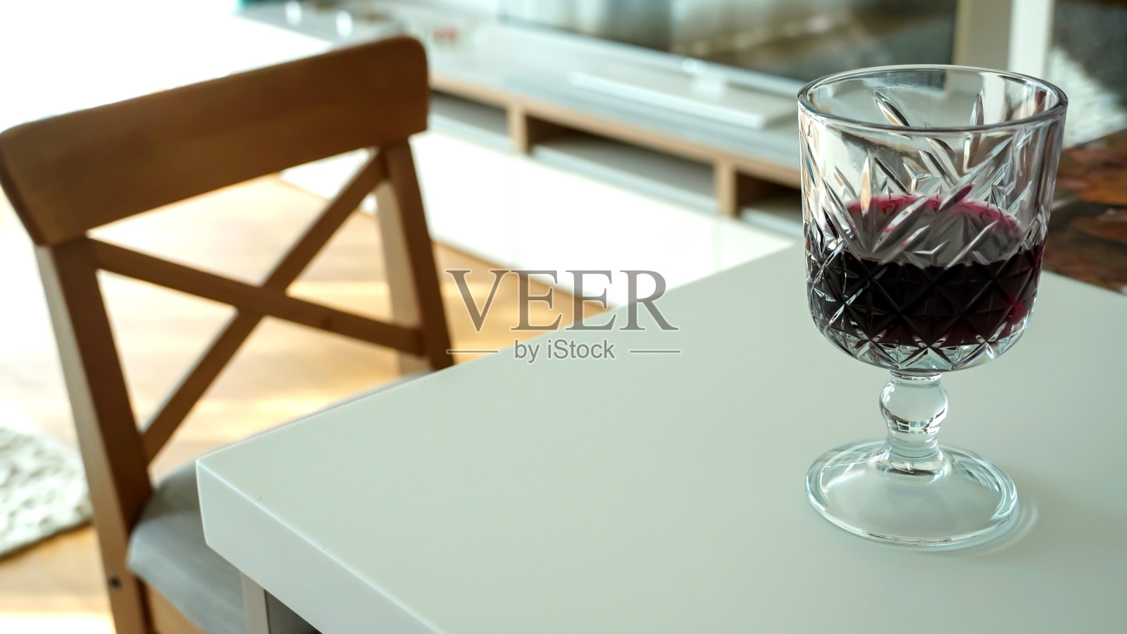 在一个装饰过的房间里，餐桌上放着一只红酒杯照片摄影图片