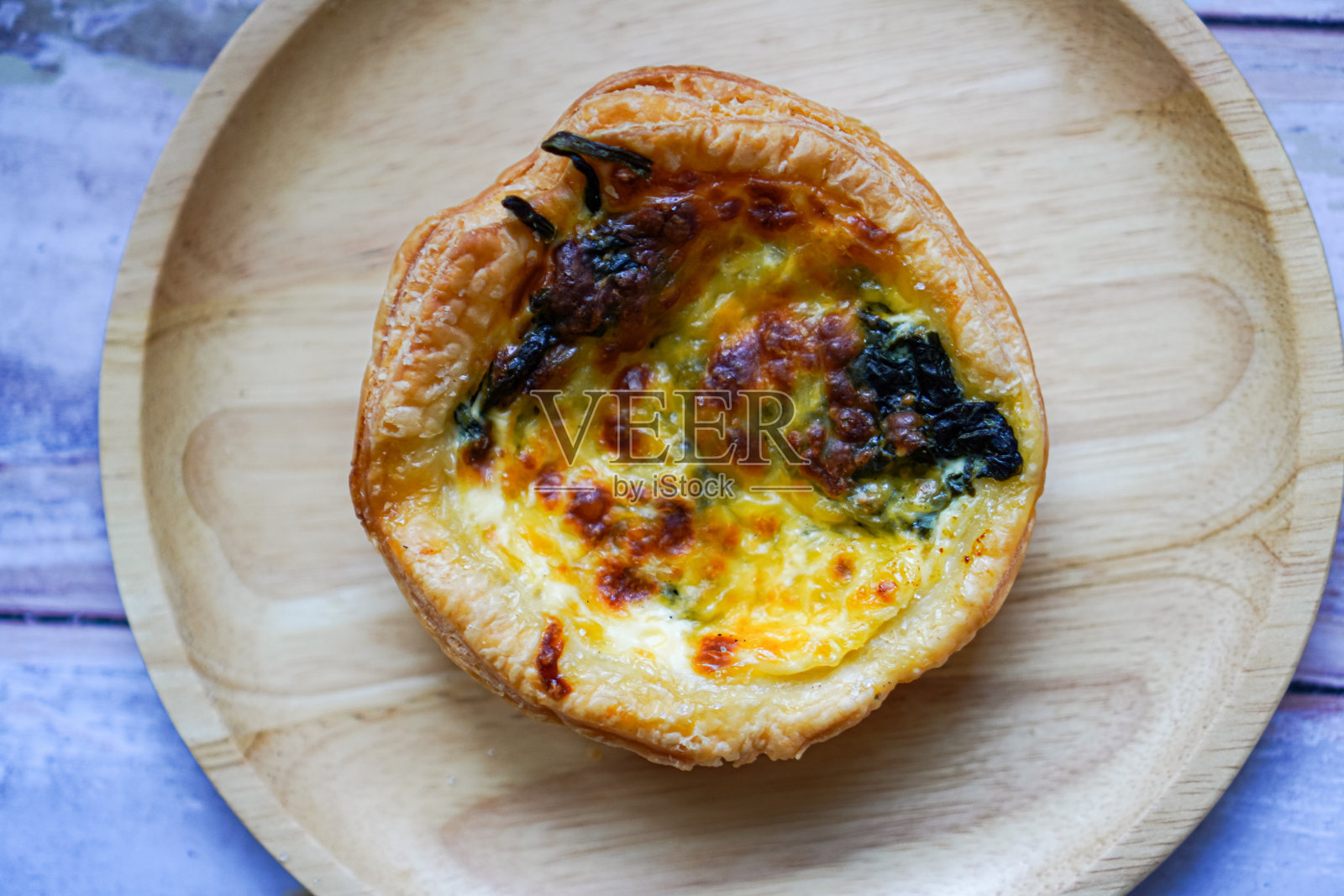 上面的图片是在木制餐盘上自制的烤菠菜和奶酪挞。照片摄影图片