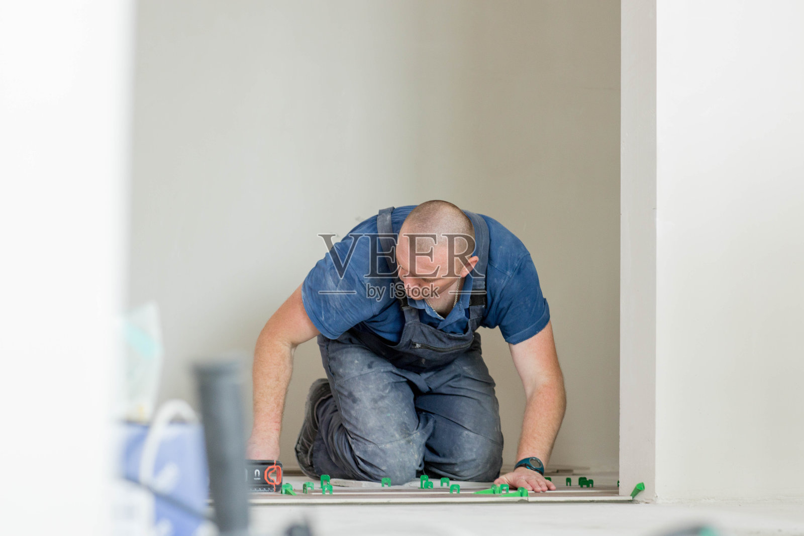 瓷砖放置瓷砖在位置上的粘合剂与鞭打瓷砖找平系统。瓷砖。照片摄影图片