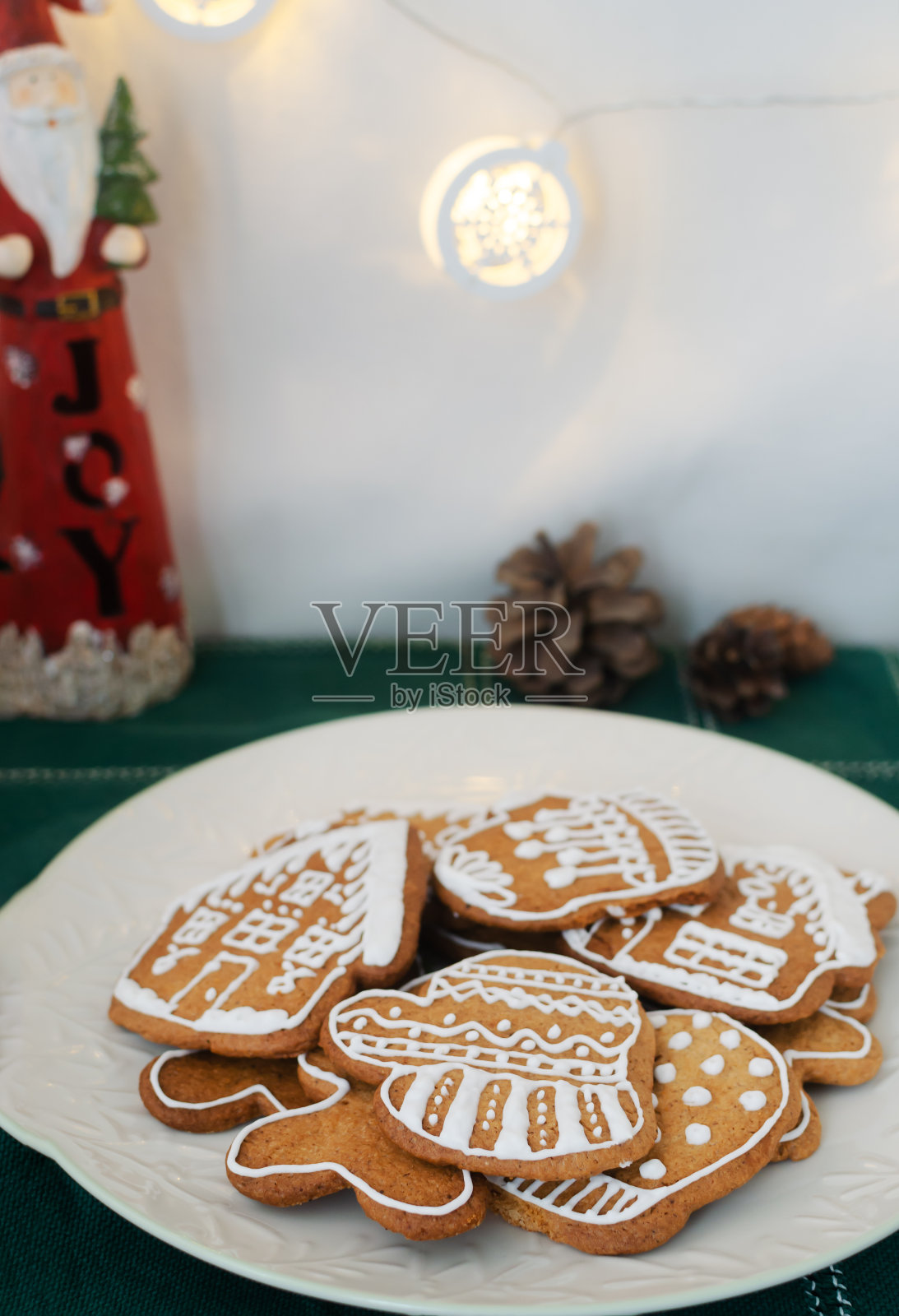 绿色格子桌布上的白色盘子里有白色糖霜的姜饼饼干。节日食品的概念。垂直方向。照片摄影图片