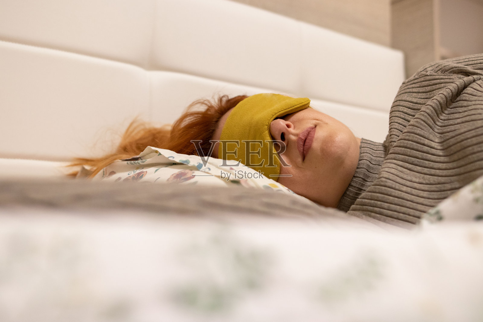 美丽的姜色女人戴着眼罩睡觉。周末心情好，放松一天照片摄影图片