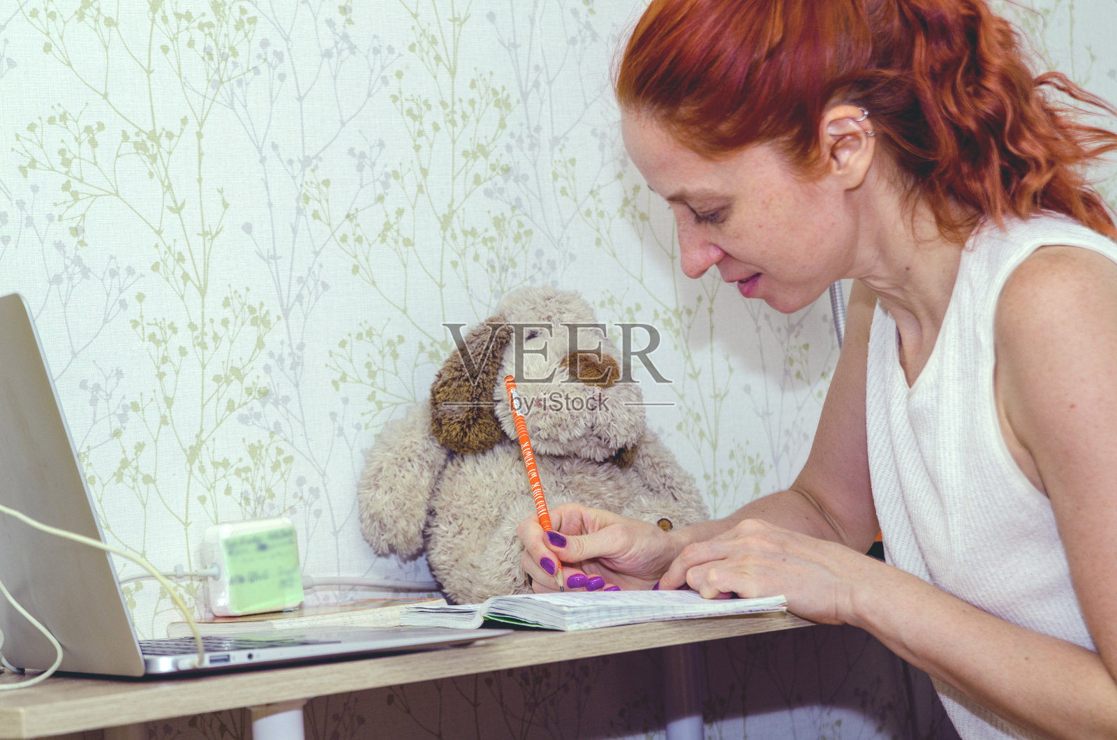 年轻女子在家学习，在她的练习本上做作业照片摄影图片