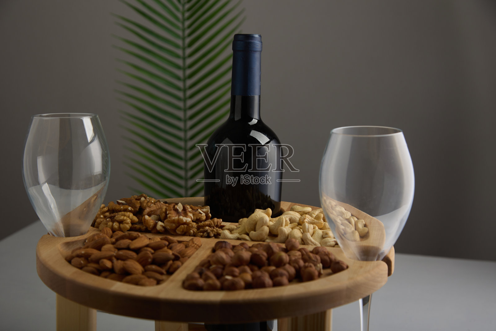 瓶酒和两个空玻璃高脚杯在胡桃木支架灰色背景照片摄影图片