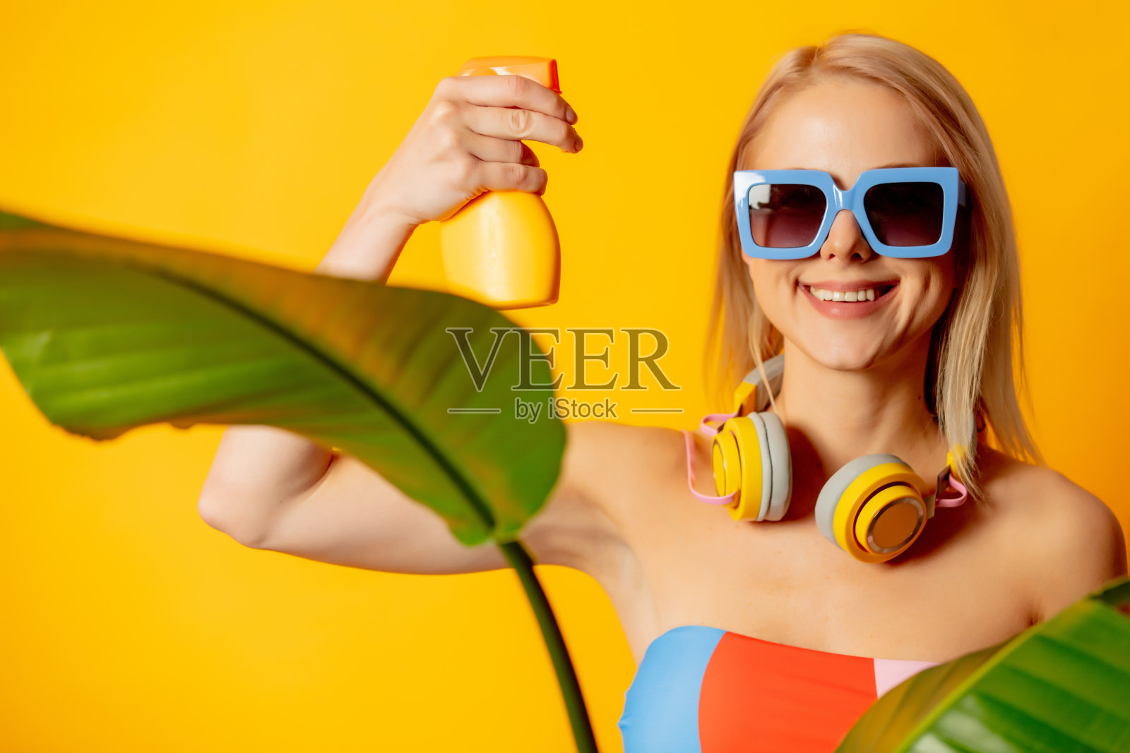 穿着彩色泳衣涂着防晒霜的金发美女照片摄影图片