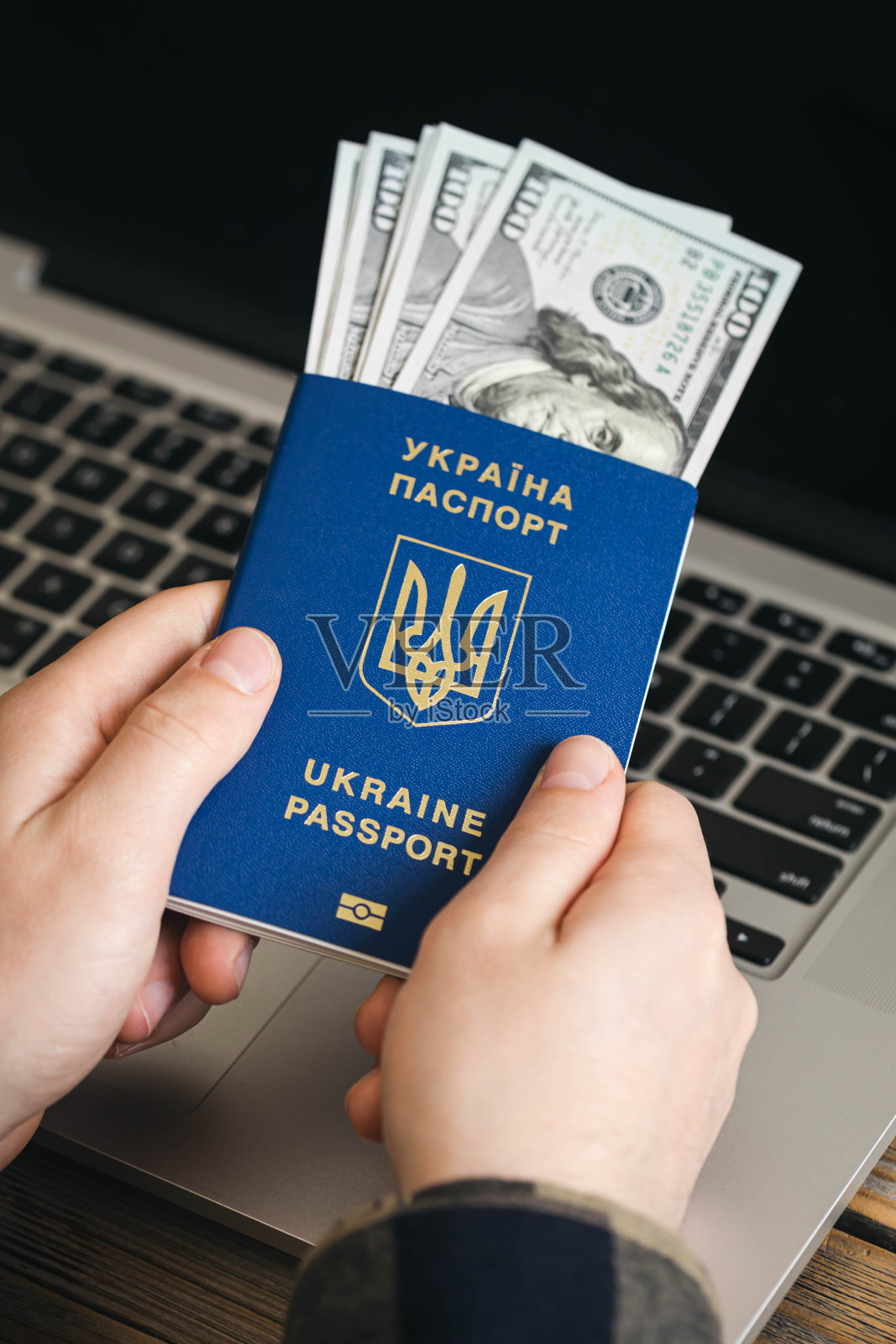 乌克兰生物识别护照和一名男子手里的美钞。照片摄影图片