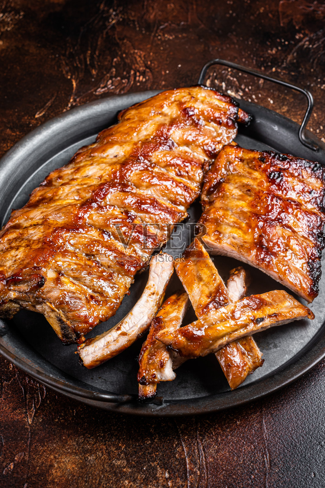 圣路易叉烧排骨，用钢制托盘用热蜂蜜腌制。黑暗的背景。俯视图照片摄影图片