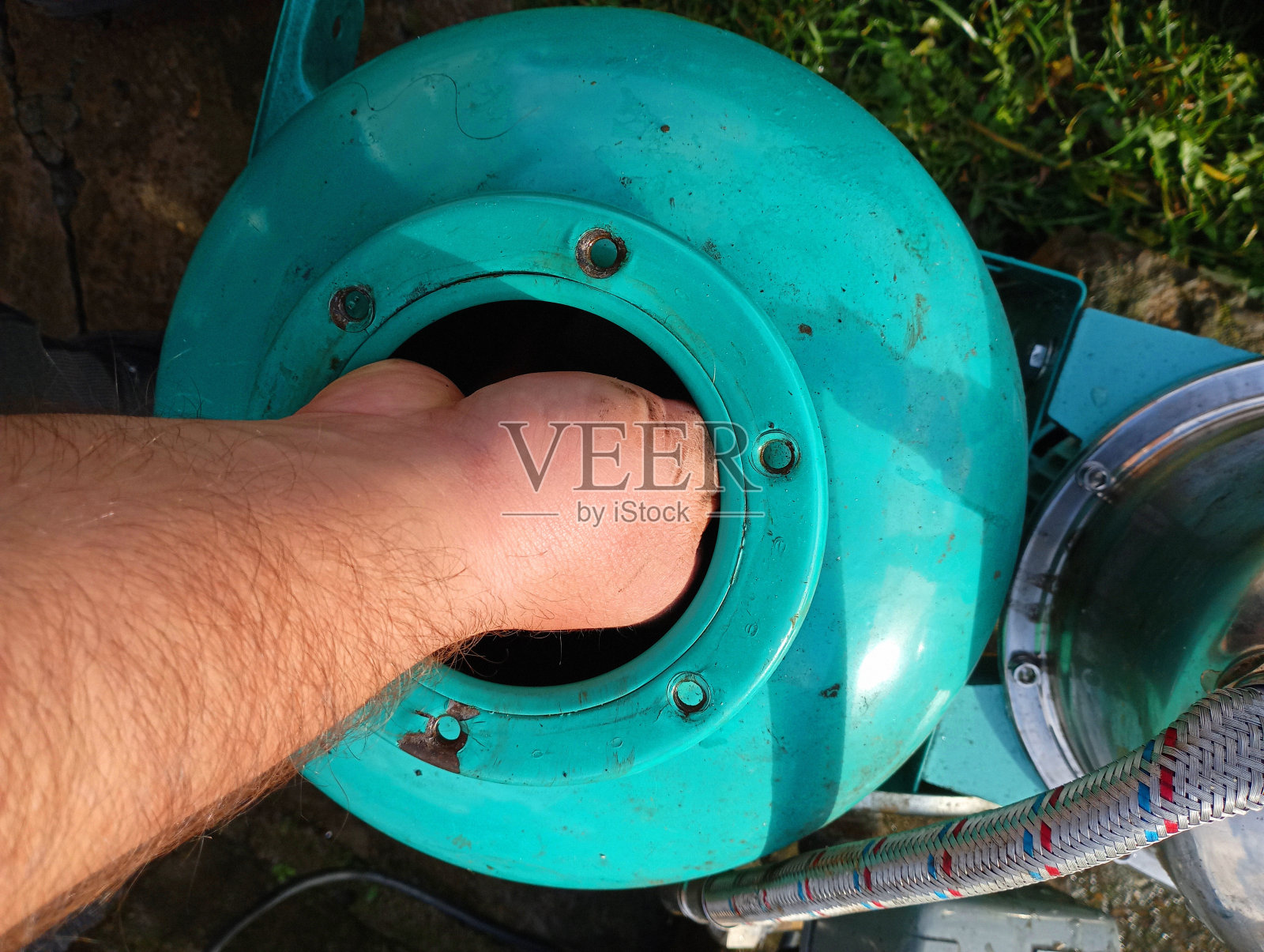 图为，一个人正在用手清洗家用绿色水泵的膨胀水箱。供水设备的维修和保养。照片摄影图片