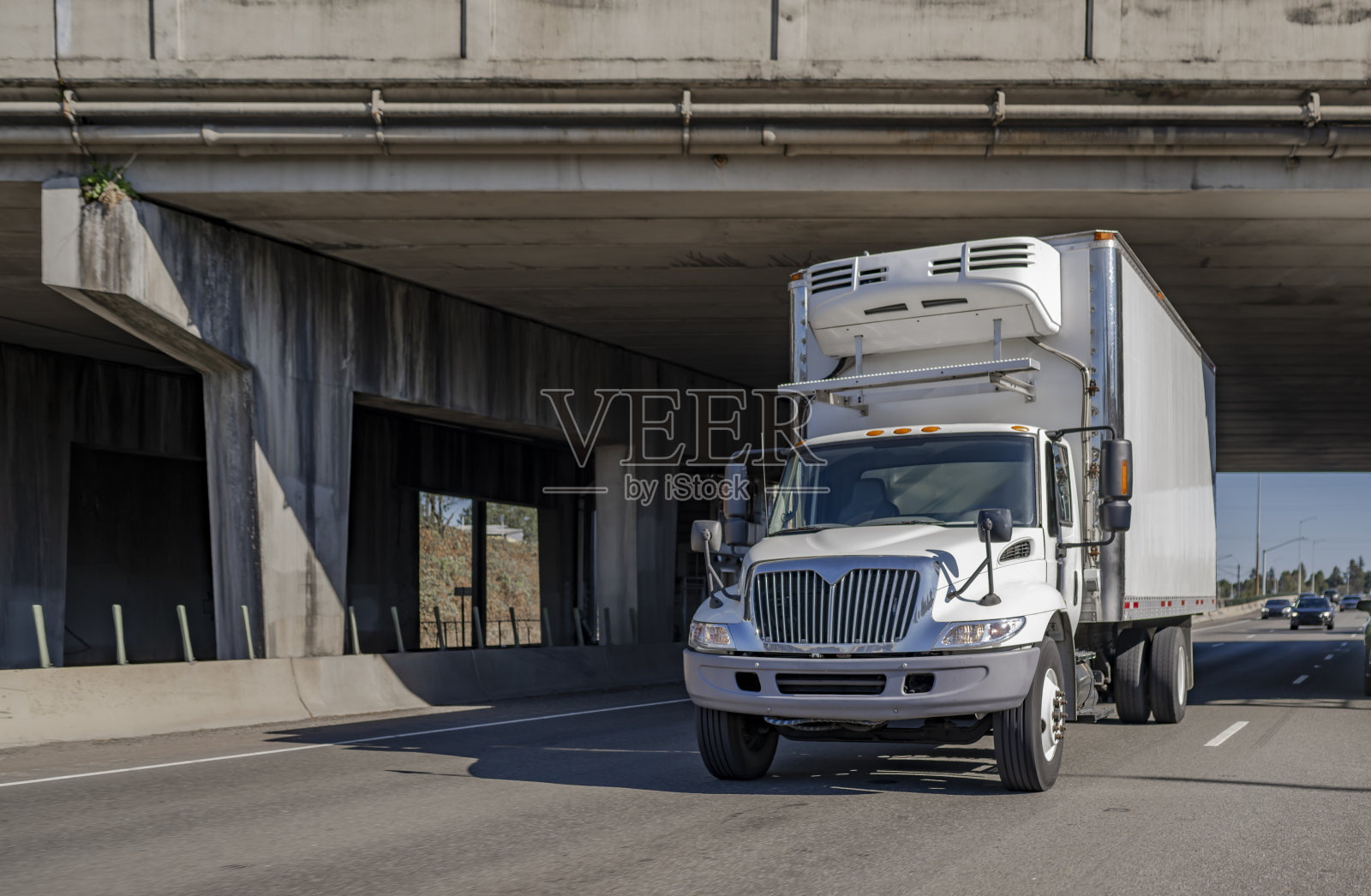 日驾驶室中型钻机半挂车运输货物在冷藏箱拖车在桥下的道路上运行照片摄影图片