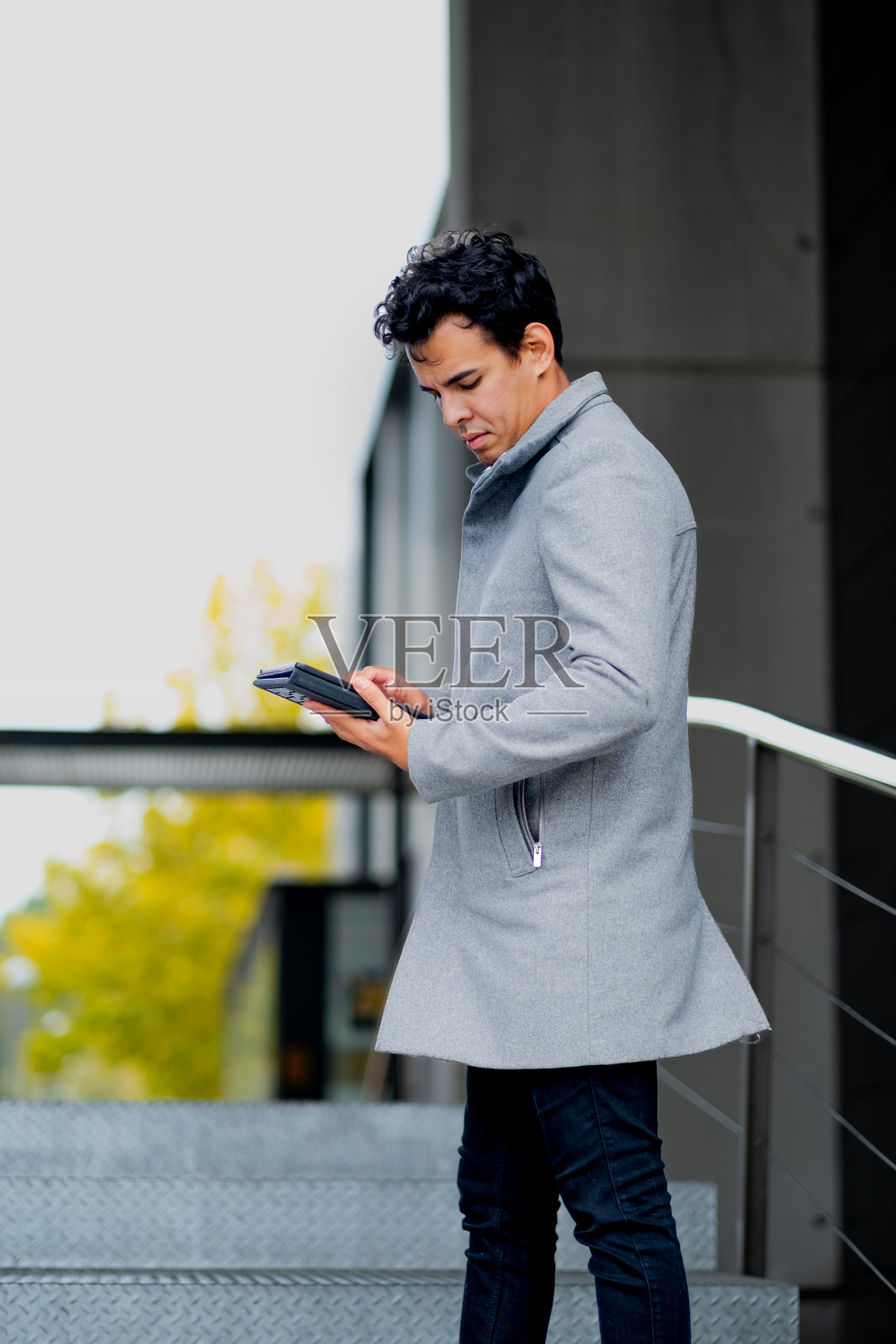 时髦的小伙子拿着写字板，秋天的云朵，马德里的背景。照片摄影图片