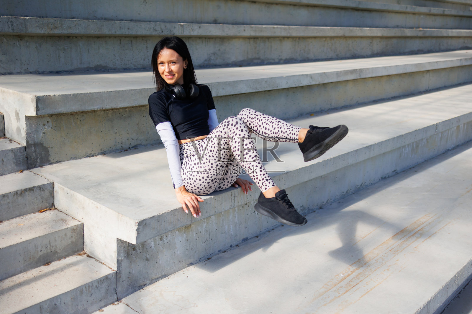 运动员的停顿:黑发女子站在体育馆楼梯上照片摄影图片