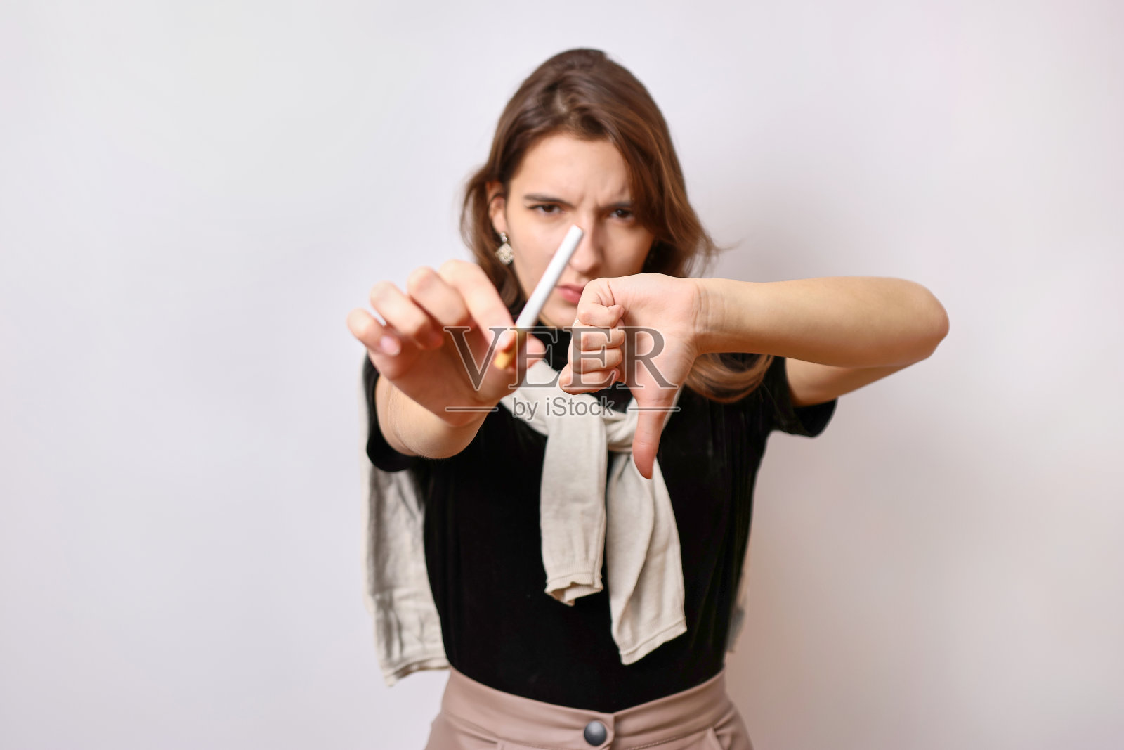 有人给了女孩一支烟，但她拒绝了，还打手势。吸烟这个坏习惯的概念。照片摄影图片