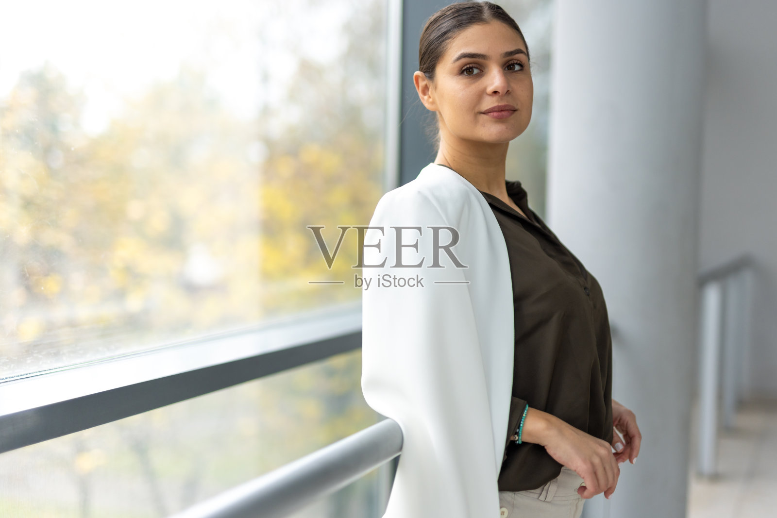 一位年轻的女商人在一座玻璃建筑的走廊里等着照片摄影图片