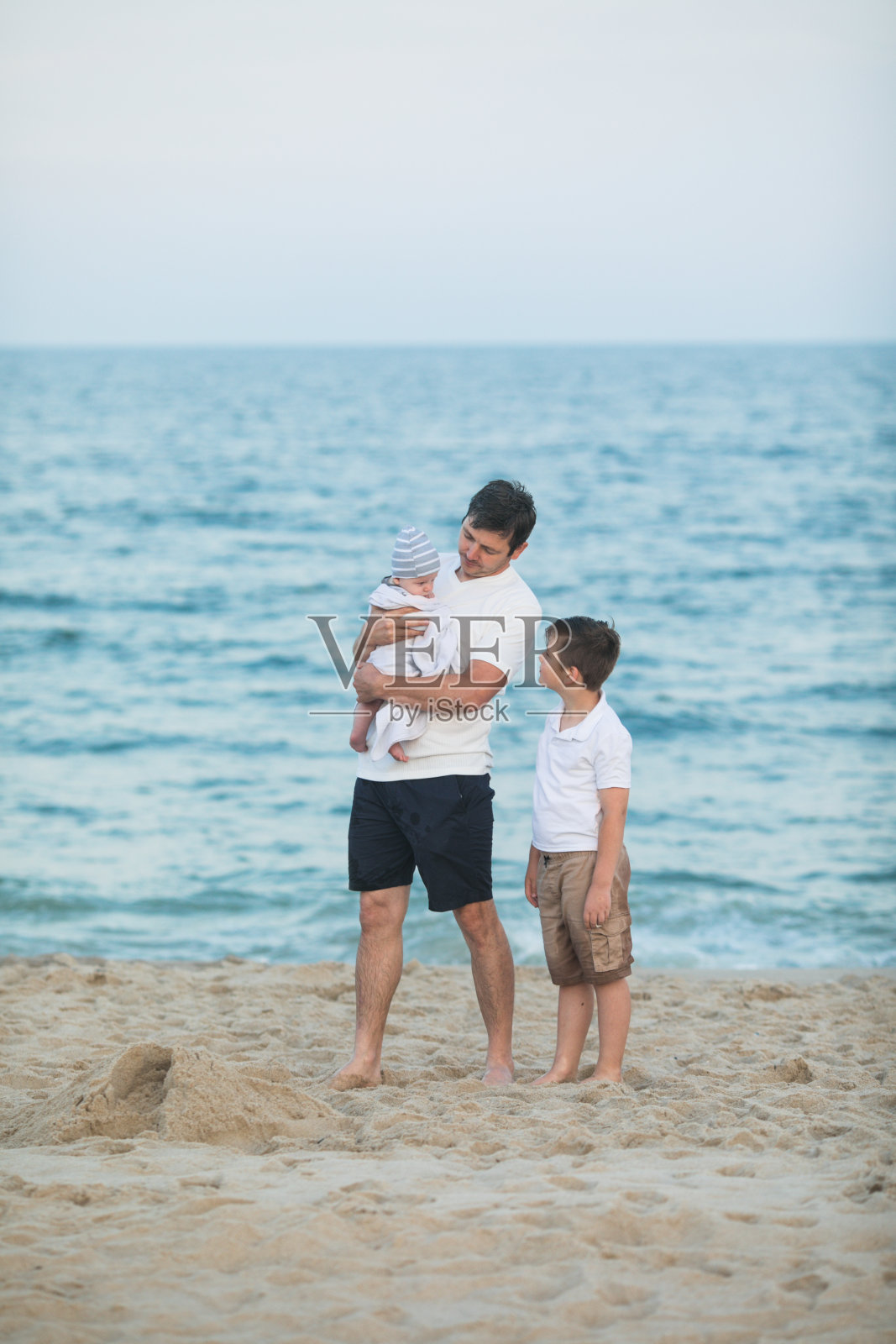 日落时分，父亲和孩子在热带海滩上玩耍。全家在海边度假胜地度暑假。阳光明媚的夜晚，爸爸和孩子们在海边玩耍。和孩子一起旅行。父母的爱照片摄影图片