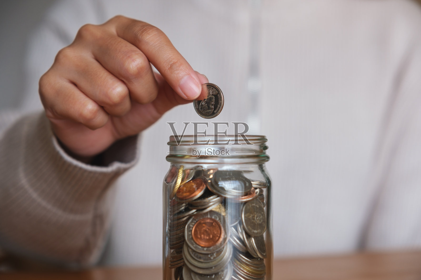 一个女人的特写图像收集和硬币放在一个玻璃罐中存钱的概念照片摄影图片