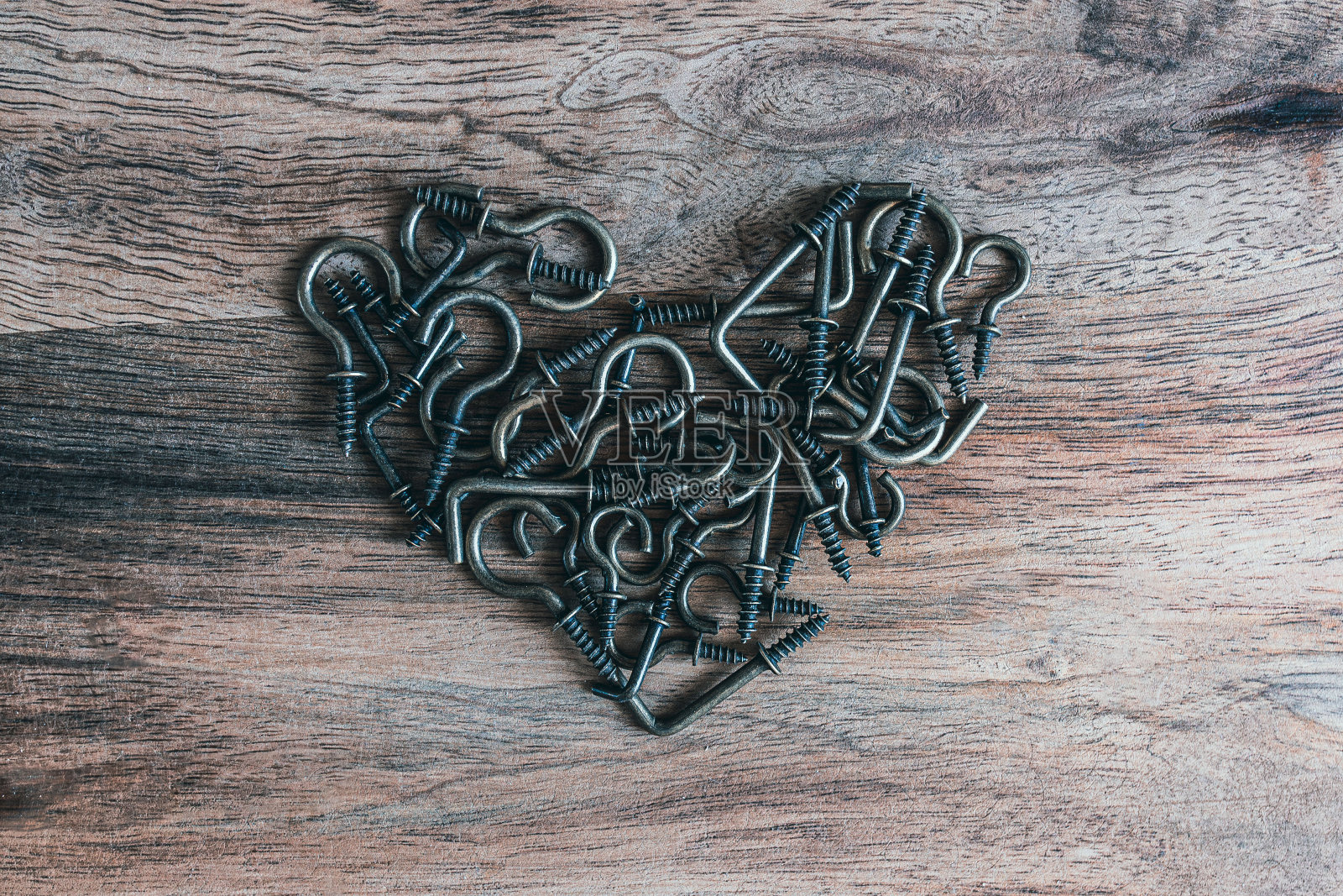 铁制的圆形和矩形钩子在木桌上呈心形摆放照片摄影图片