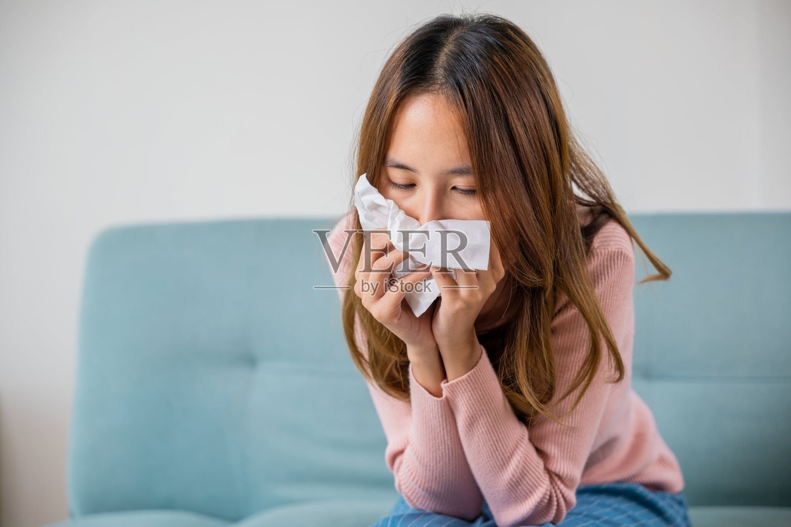 生病的亚洲年轻女子浑身冰凉，盖着毯子坐在沙发上照片摄影图片