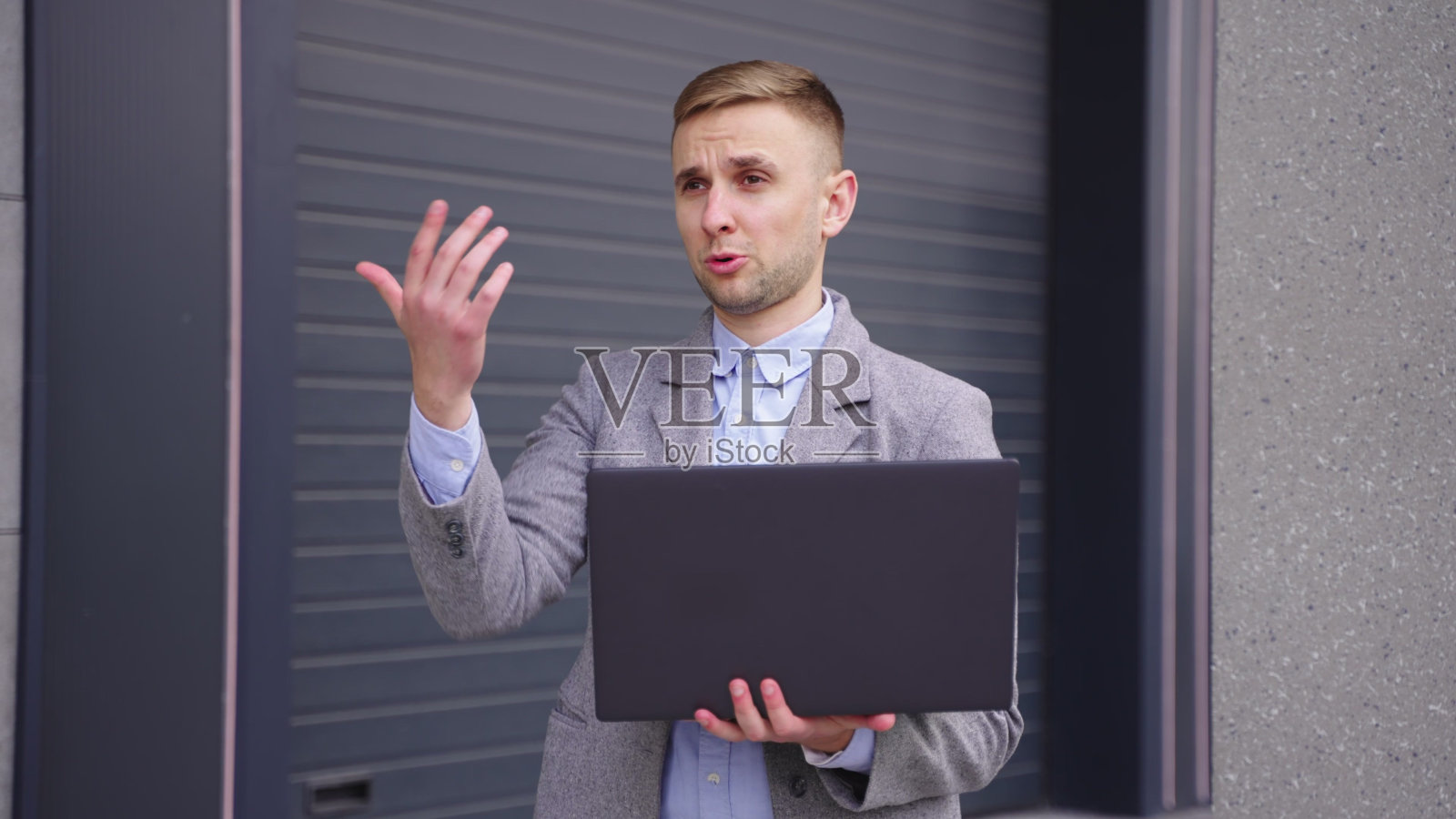 一个年轻人拿着笔记本电脑和他的同事聊天。慢动作照片摄影图片